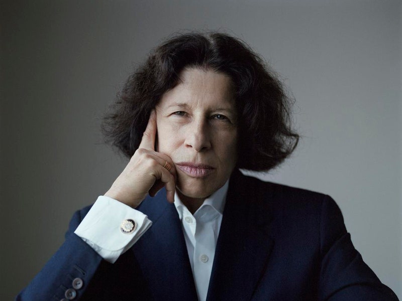 Image may contain: Fran Lebowitz, Suit, Coat, Clothing, Overcoat, Apparel, Human, Person, Sitting, and Sleeve